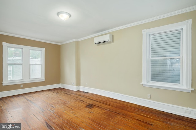 unfurnished room featuring hardwood / wood-style floors, ornamental molding, an AC wall unit, and baseboards