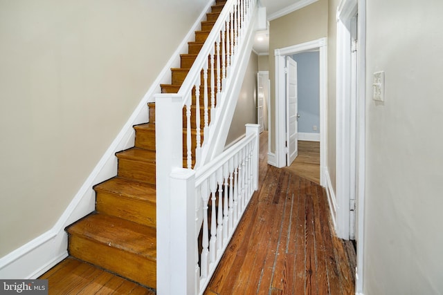 stairway with wood-type flooring, crown molding, and baseboards