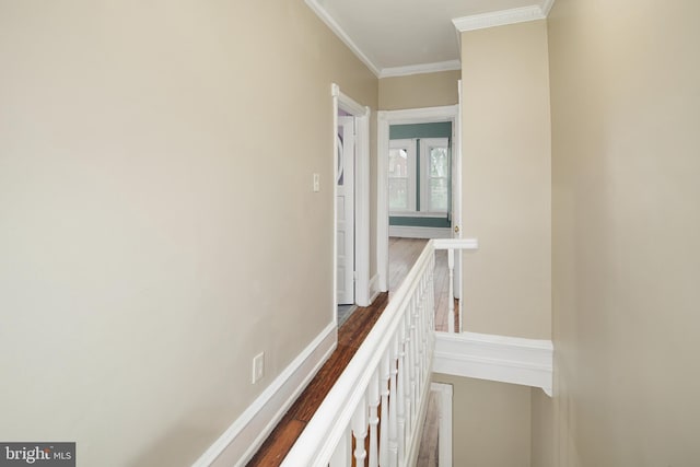 hall featuring baseboards, wood finished floors, an upstairs landing, and ornamental molding