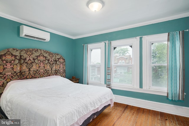 bedroom featuring a wall mounted air conditioner, baseboards, multiple windows, and wood finished floors