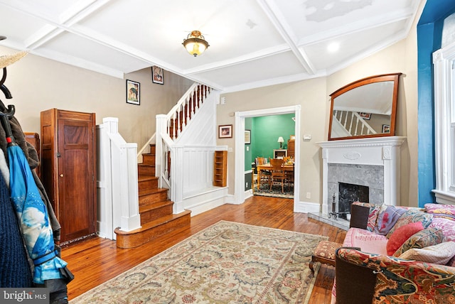 living room with coffered ceiling, stairs, baseboards, beamed ceiling, and wood finished floors