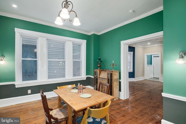 dining space featuring hardwood / wood-style floors, ornamental molding, baseboards, and a notable chandelier