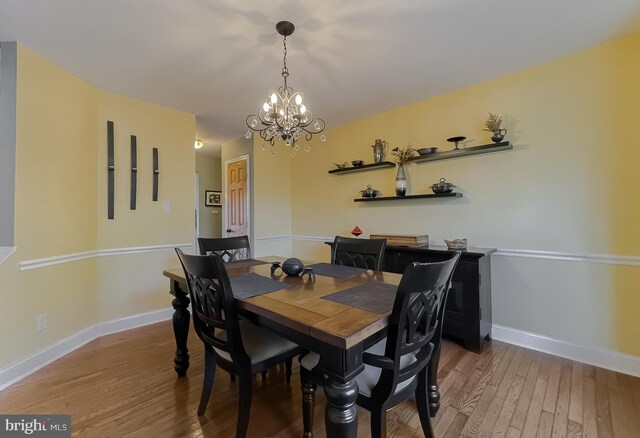 dining area with a chandelier, baseboards, and wood finished floors