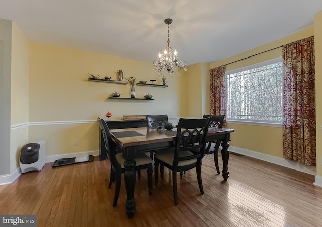 dining room with baseboards, wood-type flooring, and a notable chandelier