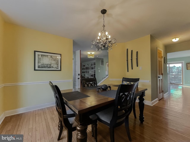 dining space with wood finished floors, baseboards, and a chandelier