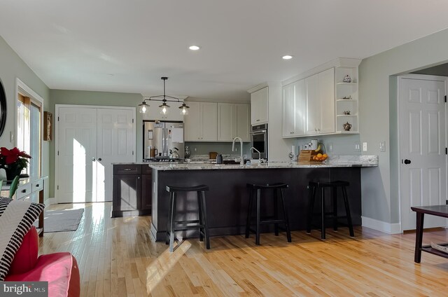 kitchen with light wood-style flooring, open shelves, white cabinetry, a peninsula, and appliances with stainless steel finishes