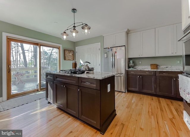 kitchen featuring dark brown cabinets, white cabinets, freestanding refrigerator, and light wood-style floors