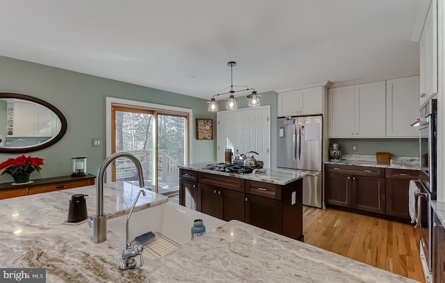 kitchen with white cabinetry, light wood-style floors, appliances with stainless steel finishes, dark brown cabinets, and hanging light fixtures