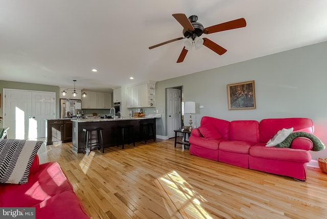 living area with recessed lighting, baseboards, light wood-style floors, and a ceiling fan