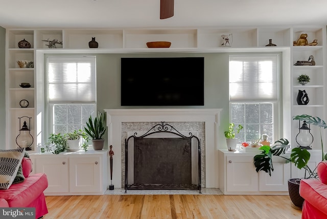 living room featuring plenty of natural light, light wood-style flooring, and a tile fireplace