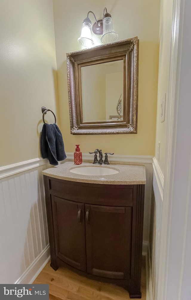 bathroom with vanity, wood finished floors, and a wainscoted wall