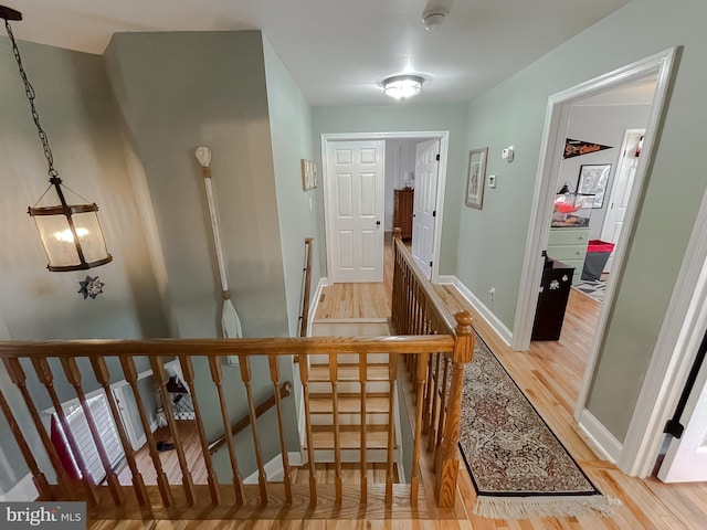 hall with an upstairs landing, light wood-style floors, and baseboards