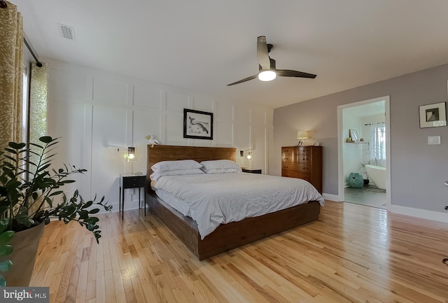 bedroom with a ceiling fan, visible vents, baseboards, light wood-style flooring, and a decorative wall