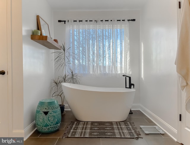 bathroom featuring tile patterned flooring, baseboards, and a freestanding tub