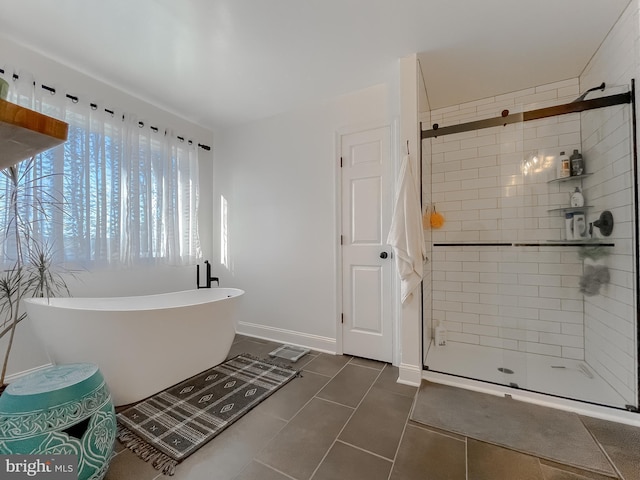 full bath with tile patterned flooring, a freestanding tub, baseboards, and a stall shower