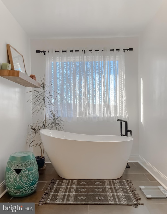 bathroom featuring a freestanding tub, baseboards, and tile patterned flooring