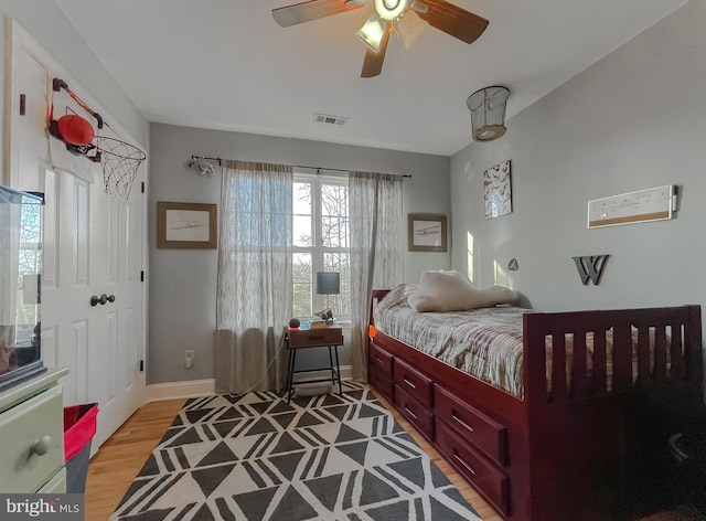 bedroom featuring visible vents, baseboards, light wood-style flooring, and a ceiling fan