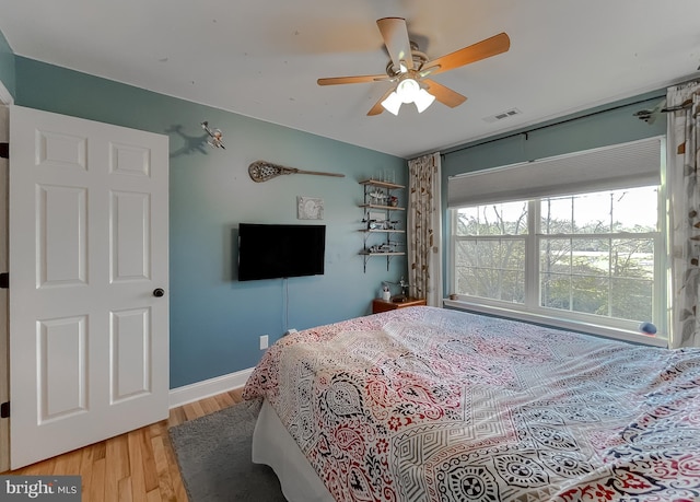 bedroom featuring ceiling fan, visible vents, baseboards, and wood finished floors