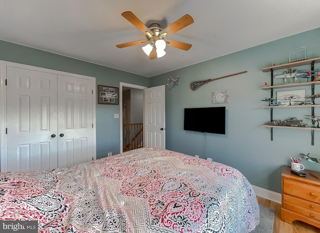 bedroom with a closet, baseboards, wood finished floors, and a ceiling fan