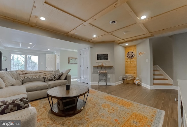 living area featuring coffered ceiling, stairs, baseboards, and wood finished floors