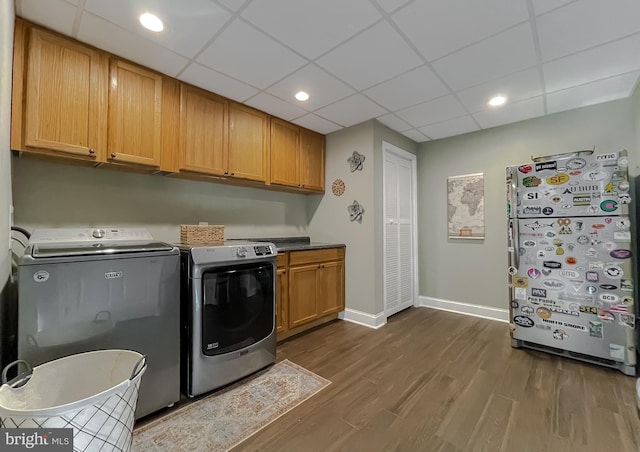 clothes washing area featuring washing machine and clothes dryer, baseboards, dark wood finished floors, recessed lighting, and cabinet space