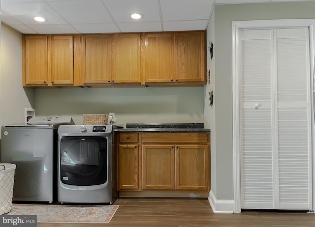 clothes washing area with separate washer and dryer, wood finished floors, cabinet space, and recessed lighting