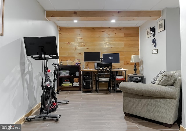 exercise area with a drop ceiling, wood finished floors, and wood walls