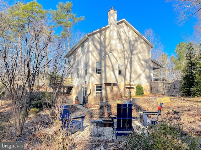 rear view of house featuring a chimney and fence