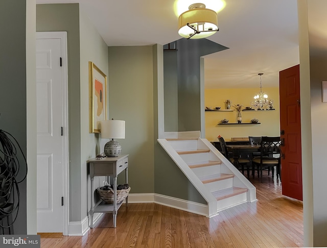 stairway featuring wood finished floors, baseboards, and a chandelier