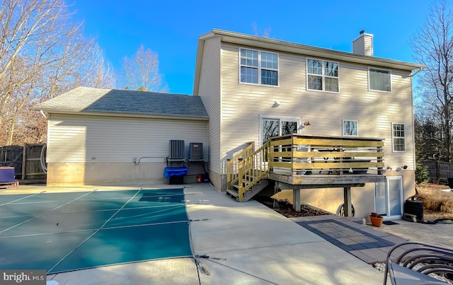 back of house featuring a deck, a patio, fence, and a chimney