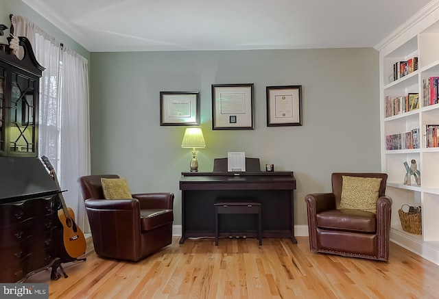 sitting room featuring built in shelves, wood finished floors, and baseboards