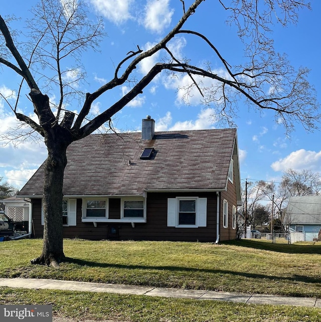 view of front of home with a shingled roof, a chimney, and a front lawn