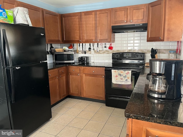 kitchen featuring light tile patterned floors, tasteful backsplash, brown cabinetry, under cabinet range hood, and black appliances