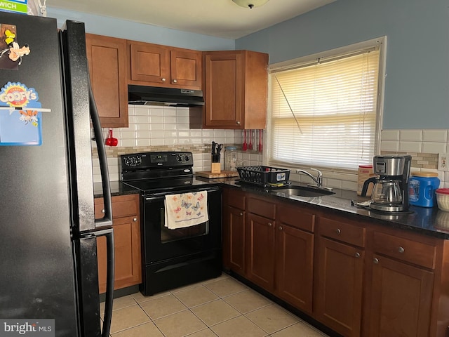 kitchen featuring light tile patterned floors, under cabinet range hood, a sink, black appliances, and brown cabinetry