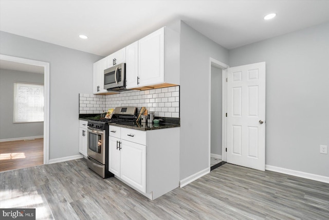 kitchen with stainless steel appliances, tasteful backsplash, white cabinets, and light wood finished floors