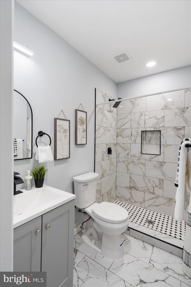 bathroom with visible vents, toilet, tiled shower, marble finish floor, and vanity