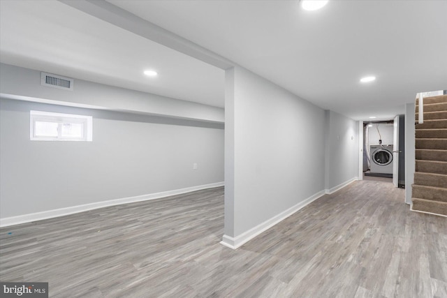 basement featuring visible vents, wood finished floors, stairway, baseboards, and washer / dryer