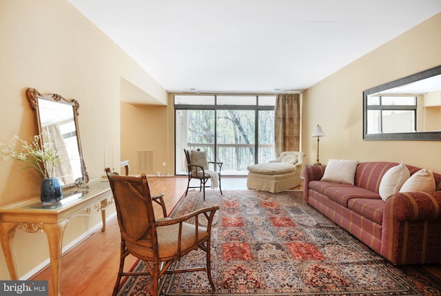 living room with visible vents, baseboards, wood finished floors, and floor to ceiling windows