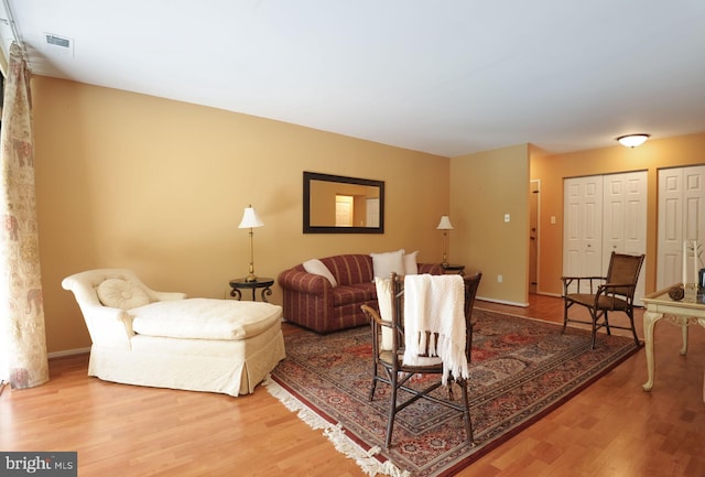 living area with wood finished floors, visible vents, and baseboards