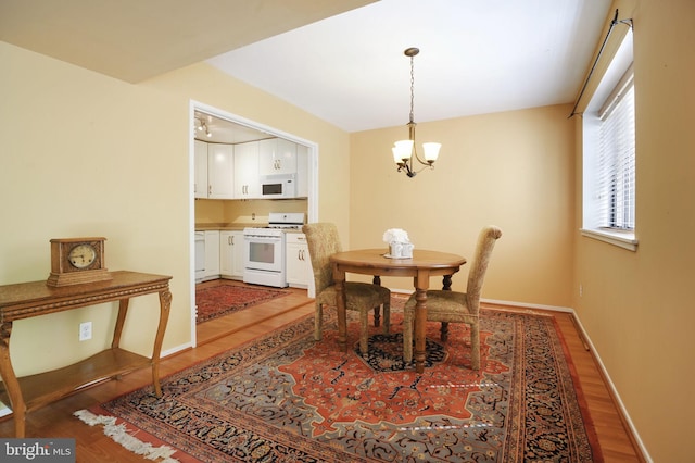 dining room with light wood-type flooring, baseboards, and a notable chandelier