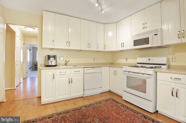 kitchen with light countertops, light wood-style flooring, white appliances, and white cabinetry