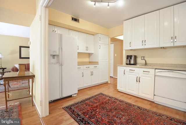 kitchen featuring light countertops, visible vents, light wood finished floors, and white appliances