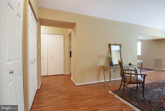 corridor featuring wood finished floors, visible vents, and baseboards