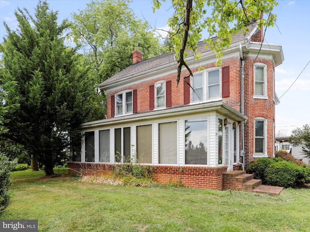 exterior space featuring a chimney, a front lawn, and brick siding