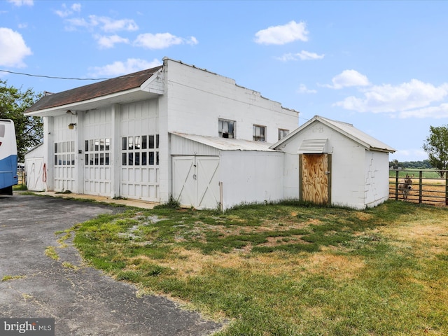 view of home's exterior with an outbuilding, a yard, board and batten siding, and fence