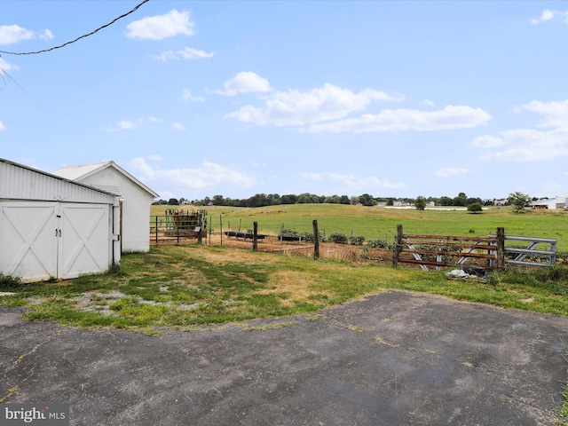 view of yard featuring an outbuilding, a rural view, and fence