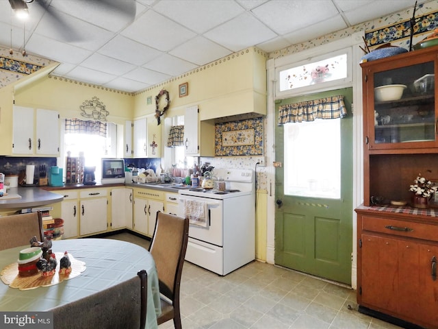 kitchen featuring a paneled ceiling, decorative backsplash, cream cabinetry, and white range with electric cooktop