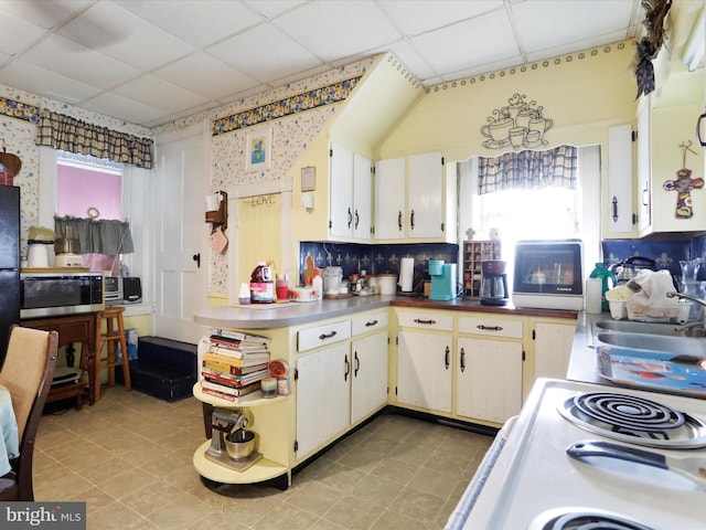 kitchen with stainless steel microwave, a sink, white electric stove, and a drop ceiling