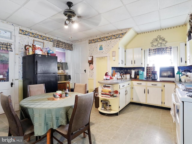 kitchen with white electric stove, stainless steel microwave, freestanding refrigerator, a drop ceiling, and a peninsula