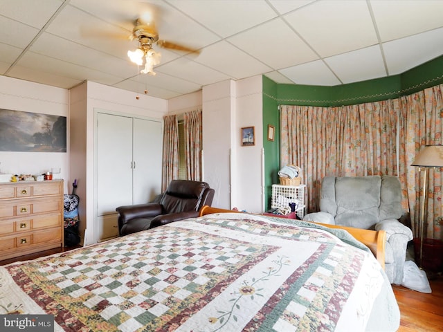 bedroom featuring a ceiling fan, a paneled ceiling, and wood finished floors